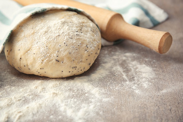 Raw dough with poppy seeds and rolling pin on table