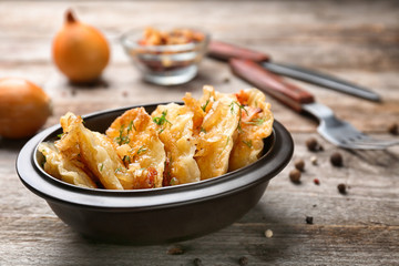 Bowl with tasty dumplings on wooden background