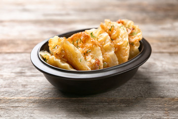 Bowl with tasty dumplings on wooden background