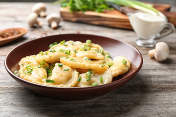 Plate with tasty dumplings on wooden background