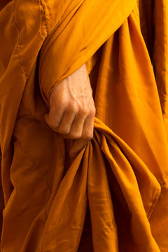 Close-up of monk hands holding his robes.
