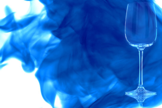 Empty white wine glass enveloped in blue smoke.