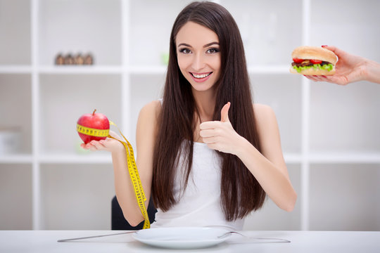 Diet. Beautiful Young Woman choosing between Fruits and Junk food