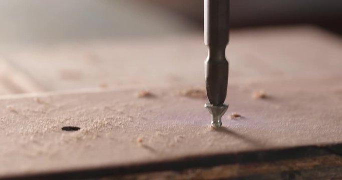 Craftsman drives the screw into the wooden board