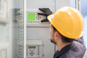 Maintenance engineer testing voltage switchgear and bay control unit