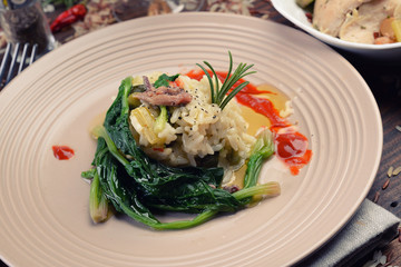 Tricolor risotto surrounded by spinach and gravy