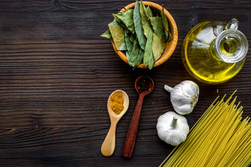 Cook a meal. Template for menu design. Mock up for menu or recipe. Empty space near ingredients. Raw pasta, oil, garlic, spices on dark wooden background top view copy space