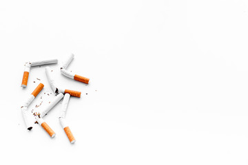 Smoking. Half-smoked cigarettes with ash on white background top view copy space