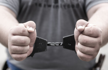 Hand criminal in handcuffs the focus on his fists close up. Arrest detention criminal