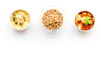 Middle Eastern cuisine. Bowls with hummus and chickpeas on white background top view copy space