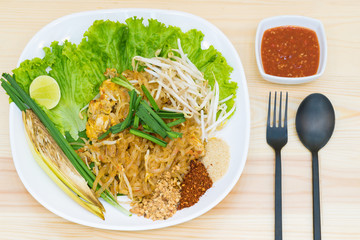 Top view food : Pad Thai, Stir-fried rice noodle with egg, tofu on wooden table. Famous Thai street food in Thailand.
