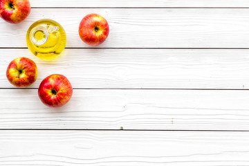 Apple cider vinegar in bottle among fresh apples on white wooden background top view copy space