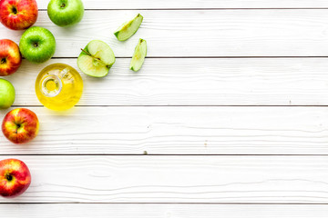 Fototapeta na wymiar Apple cider vinegar in bottle among fresh apples on white wooden background top view copy space