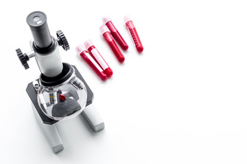 Blood analysis in clinacal lab. Test tubes near microscope on white background top view copy space