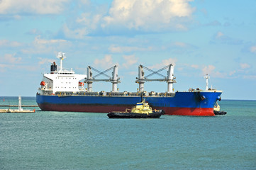 Tugboat assisting bulk cargo ship