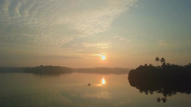 Aerial view of sailboat sailing out of a waft of mist in the lake drone footage