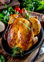 Roasted chicken with rosemary served on black plate with sauces on wooden table, close up © lblinova