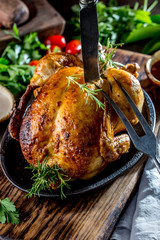 Roasted chicken with rosemary served on black plate with sauces on wooden table, close up