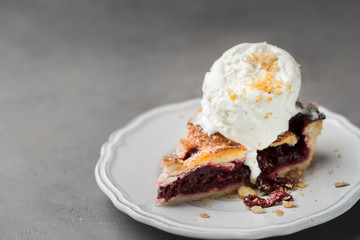A piece of cherry pie with vanilla ice cream on a white vintage plate on a gray light concrete background. Copy Space. View blank space for text.