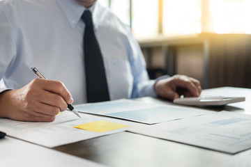 Business man working at office with laptop, tablet and graph data documents on his desk