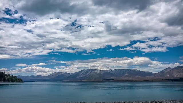 Time lapse of mesmerizing clouds moving over the serene water of lake Tekapo known for its beautiful turquoise color. Canterbury Region, New Zealand, South Island.
