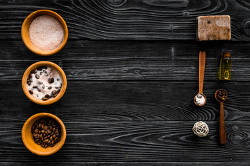 Cosmetics for skin care and relaxation. Chocolate brown spa salt on dark wooden background top view copy space