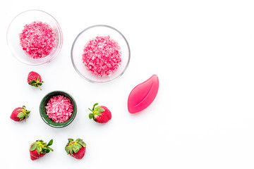 Fototapeta premium Cosmetics for skin care and relaxation. Strawberry pink spa salt on white background top view copy space