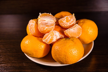 Plate with mandarins on a dark wooden table