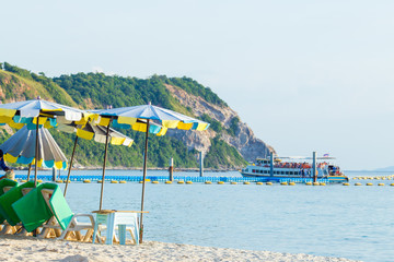 Chair with beach umbrella and boat tour at Koh Lan Thailand.