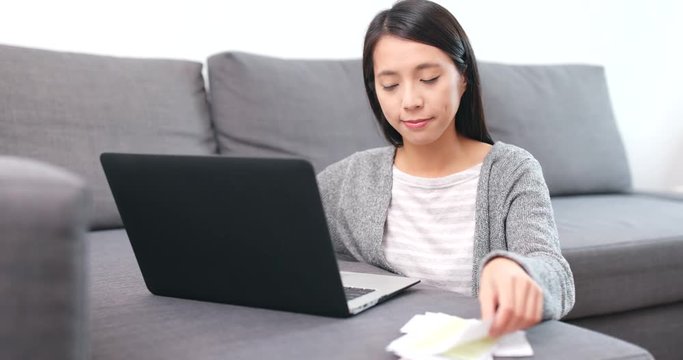 Woman using notebook computer for recording the expense