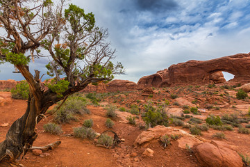 Storm clouds, rain, and red geologic sandstone structures in the Utah desert, Arches National Park