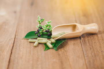 Herbal medicine capsules from herb on rustic wooden table for healthy eating and good life ,soft focus.