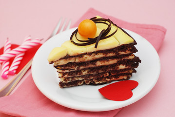 Chocolate Piece of Cake with Paper Hearts and Candles, on pink background. Party or Birthday Dessert in white Plate.