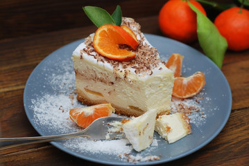 Cheesecake with Tangerines Fruit on Grey Plate and Sugar Powder. Dark Wooden Table and fork. Eatting Process.