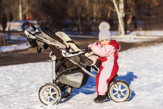little child is sitting in a stroller in winter