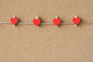 Fototapeta premium Red hearts shape pins garland over brown craft recycle cork board background. Free copy space. Valentine's day concept.