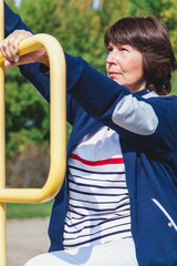 Obraz premium elderly woman performs squatting on summer sports ground