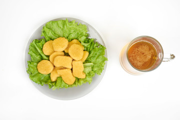 chicken nuggets , vegetables on a white plate, and beer isolated on white