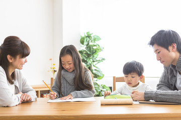 勉強する子供と勉強を見る親