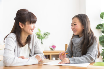 勉強する子供と勉強を見る親