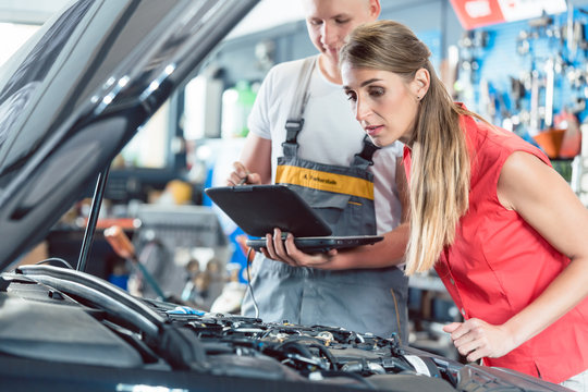 Reliable Auto Mechanic Showing To A Female Customer The Engine Error Codes Scanned By A Car Diagnostic Software In A Modern Automobile Repair Shop