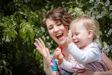 Mother and daughter have fun in the park and apple tree with white flowers