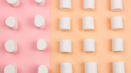 Sweet marshmallows on pastel yellow and pink background.