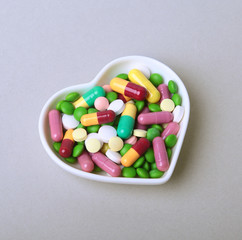 colorful assortment pills and capsules on plate.