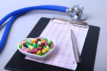 Stethoscope, RX prescription and colorful assortment pills and capsules on plate.