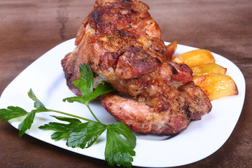 Juicy pork neck chops are grilled with potatoes on a white plate.