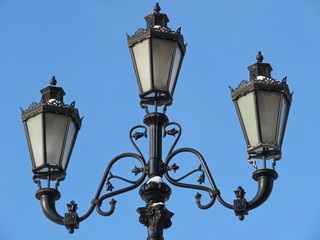 Fototapeta na wymiar Street lamp on the background of blue sky. Snowy metal streetlight isolated
