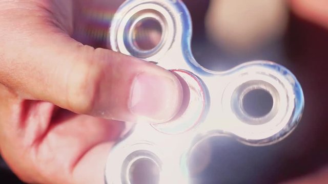 Close up of man's hand is held by a spinning spinner in his hand. slow motion. The silver spinner reflects the rays of the sun. 1920x1080