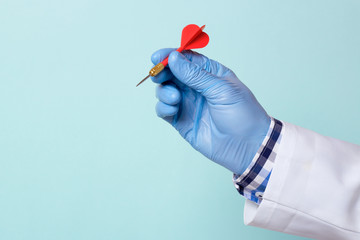 Doctor in a glove holds a red dart. Copy space for text