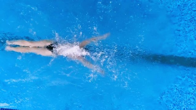 Powerful professional swimmer training in pool. Slow motion.
